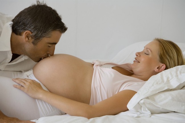 муж целует живот беременной жены