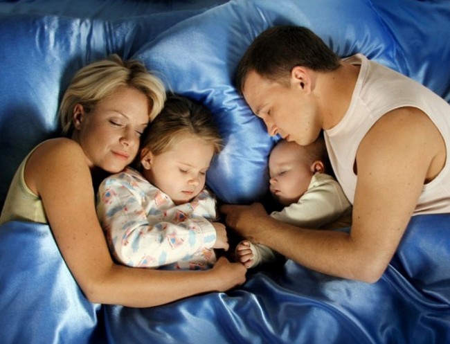 Родители и двое детей спят в одной кровати